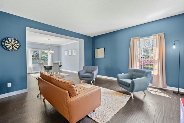 living room with baseboards, an inviting chandelier, and wood finished floors