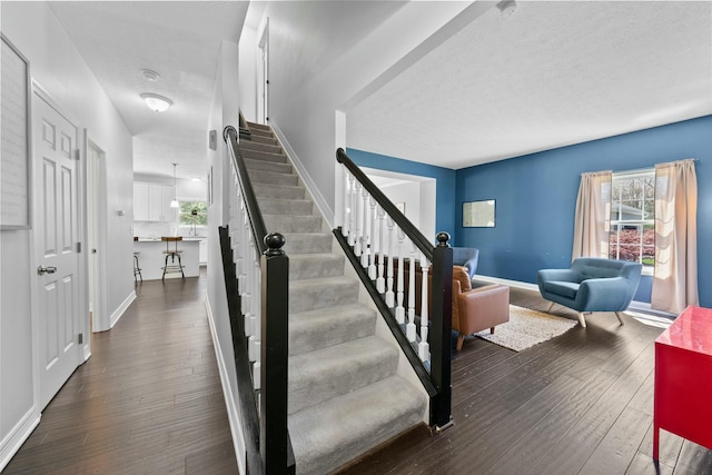 stairway featuring baseboards, wood finished floors, and a wealth of natural light