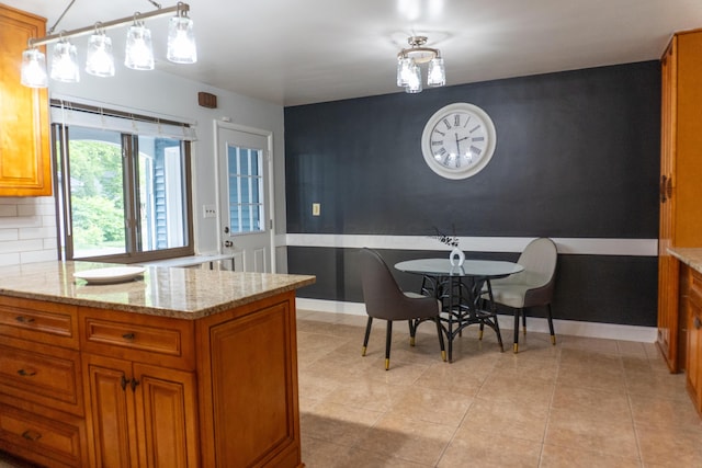 173 S Chesterfield Rd, Columbus, OH 43209 - kitchen with brown cabinetry, light stone countertops, baseboards, and an accent wall