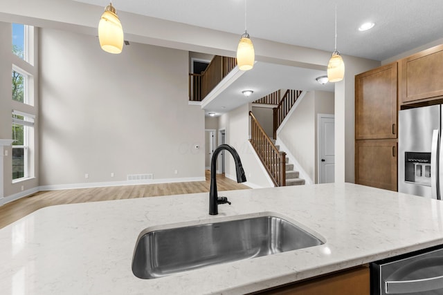 1206 Clover St, Sunbury, OH 43074 - kitchen featuring brown cabinetry, pendant lighting, a sink, and light wood-style floors