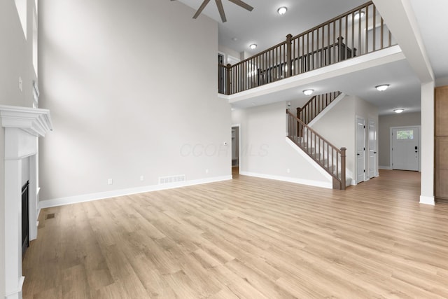 1206 Clover St, Sunbury, OH 43074 - unfurnished living room featuring a high ceiling, ceiling fan, a fireplace, visible vents, and stairway
