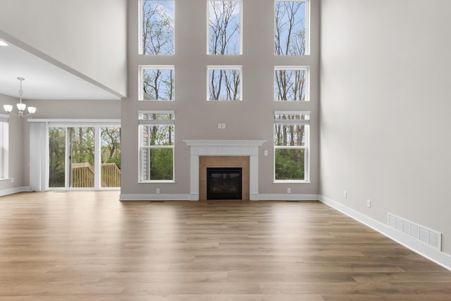 1206 Clover St, Sunbury, OH 43074 - unfurnished living room featuring visible vents, a high ceiling, a notable chandelier, and a tiled fireplace