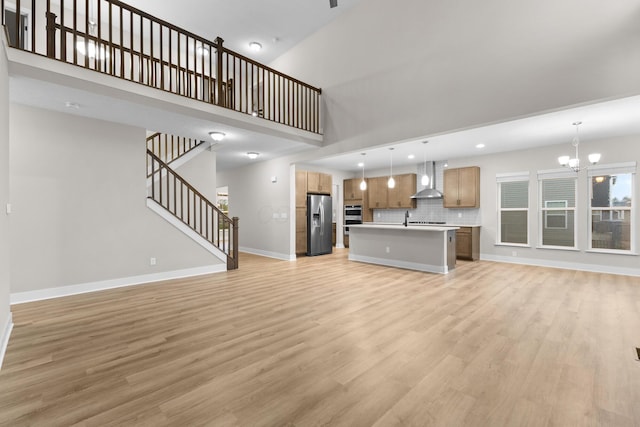 1206 Clover St, Sunbury, OH 43074 - unfurnished living room with baseboards, a towering ceiling, light wood-style flooring, and a chandelier
