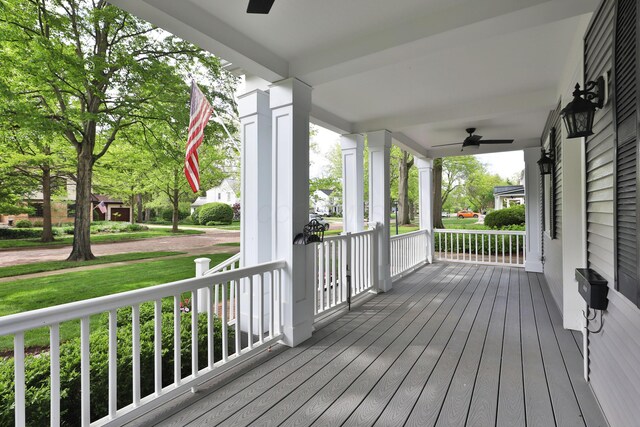 wooden terrace featuring ceiling fan, covered porch, and a yard