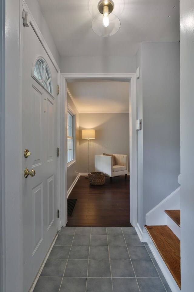 foyer entrance featuring dark tile patterned flooring, baseboards, and stairway