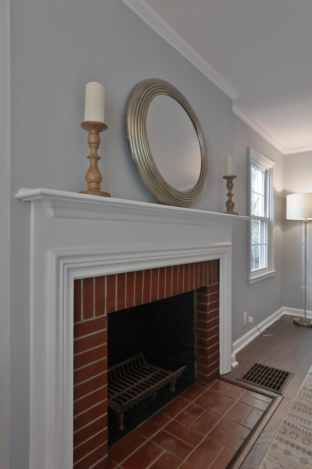 detailed view of a brick fireplace, crown molding, and baseboards