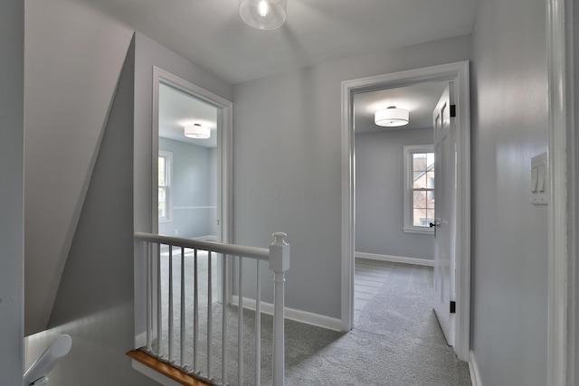 corridor featuring an upstairs landing, carpet floors, and baseboards