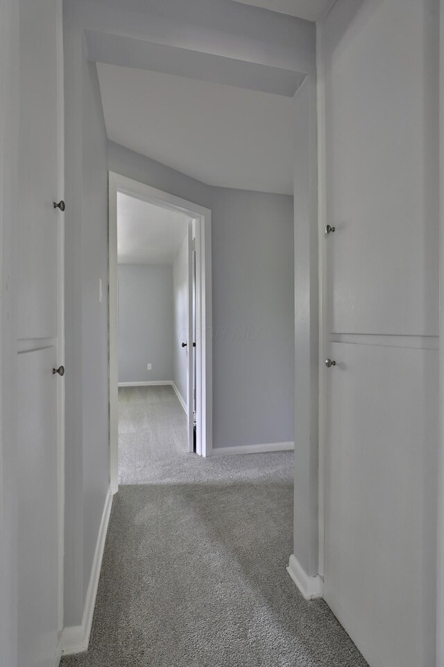 hallway with carpet flooring and baseboards