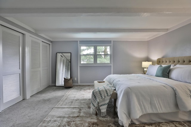 carpeted bedroom with beamed ceiling and two closets
