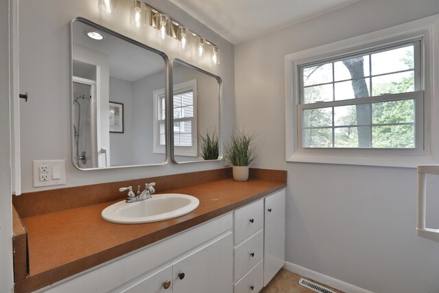 bathroom featuring vanity, baseboards, a shower, and tile patterned flooring