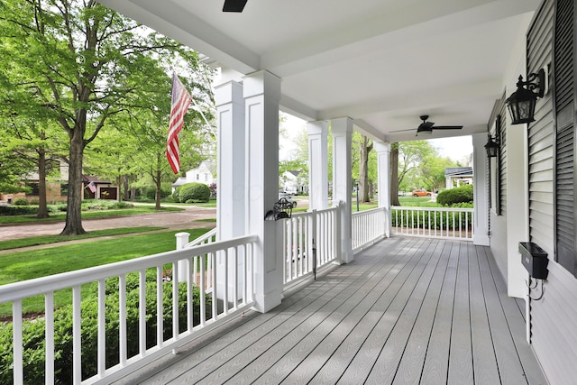 wooden terrace with a ceiling fan, a porch, and a lawn