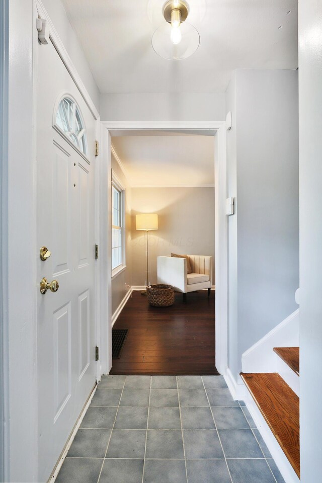 foyer featuring tile patterned floors, baseboards, and stairway