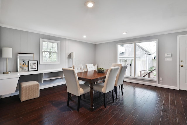 dining space with crown molding, dark wood-type flooring, baseboards, recessed lighting, and a decorative wall