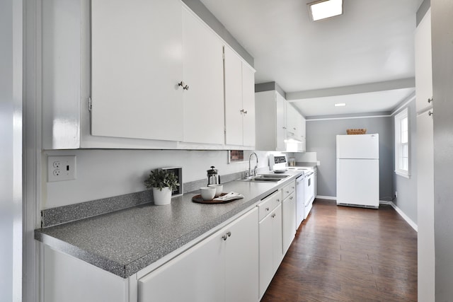kitchen featuring white appliances, a sink, white cabinets, dark wood-style flooring, and baseboards