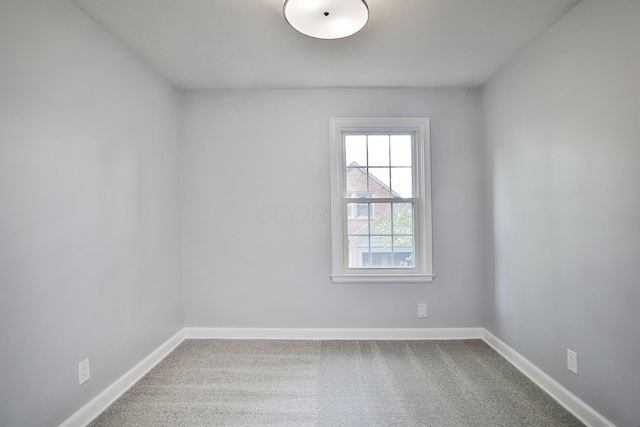 carpeted empty room featuring baseboards