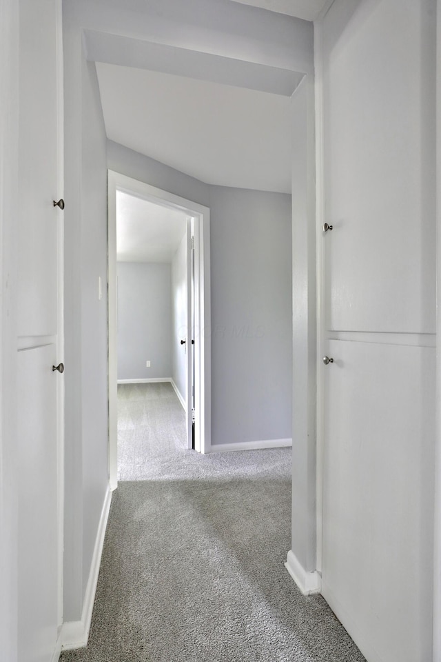 hallway featuring carpet floors and baseboards