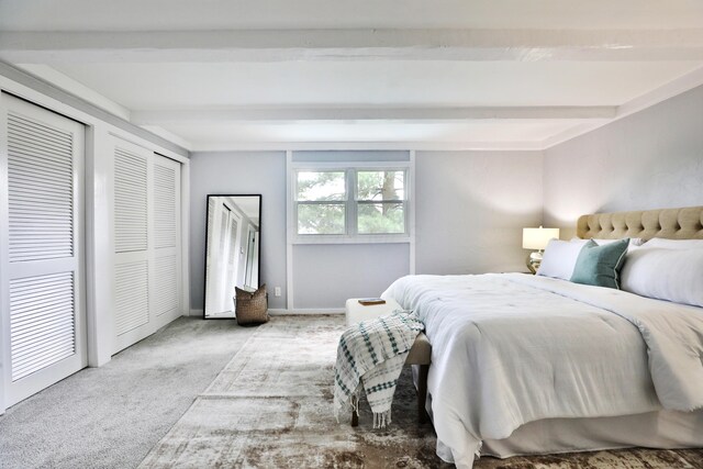 carpeted bedroom featuring beam ceiling and multiple closets