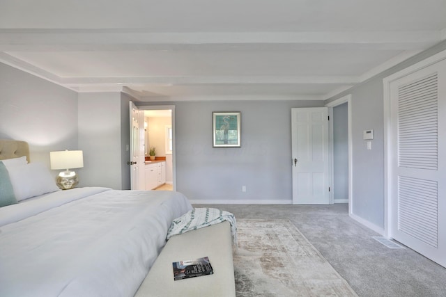 carpeted bedroom with baseboards, beam ceiling, ensuite bath, and a closet