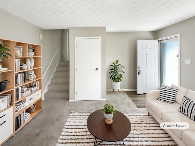 living area with baseboards, stairs, and a textured ceiling