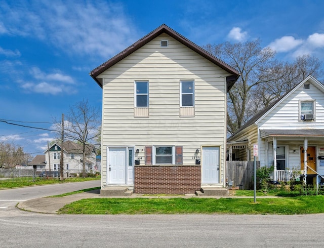 traditional-style home with a front lawn, brick siding, and fence