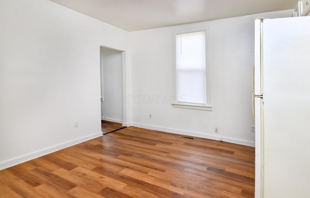 empty room with baseboards, visible vents, wood finished floors, and plenty of natural light