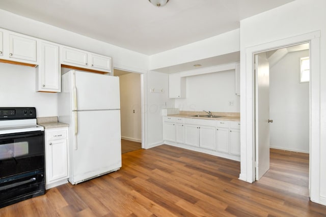 kitchen with white cabinetry, electric range oven, light countertops, and freestanding refrigerator