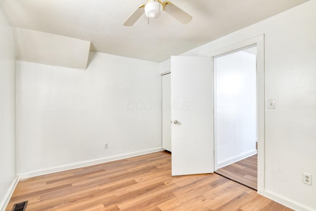 interior space featuring baseboards, visible vents, a ceiling fan, and light wood-style flooring