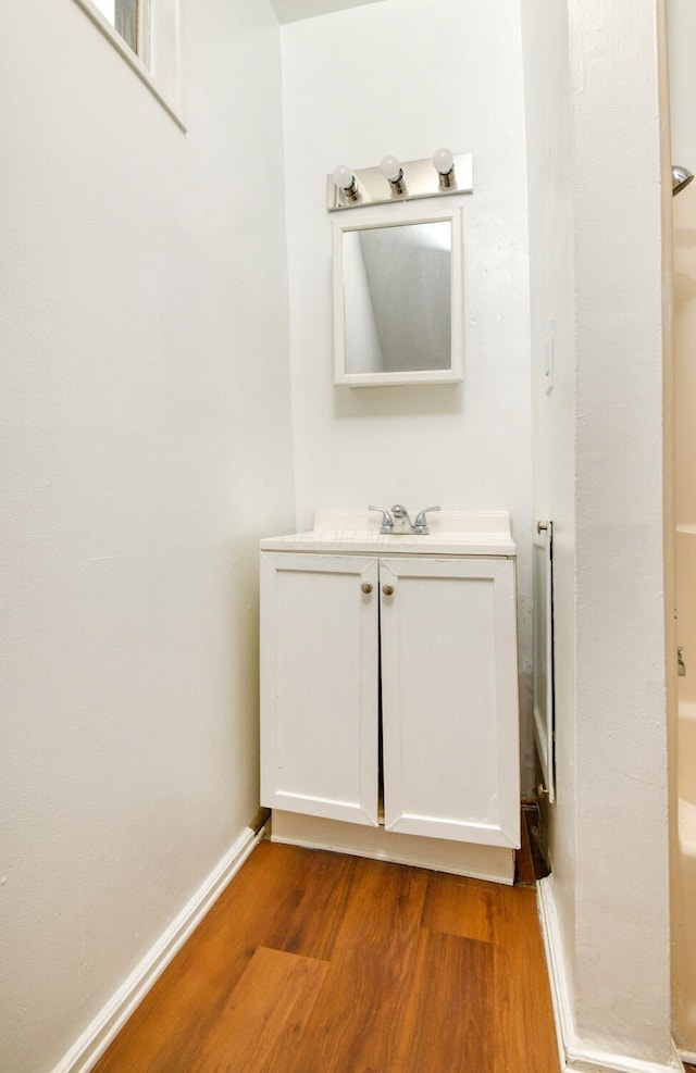 bathroom with wood finished floors, vanity, and baseboards