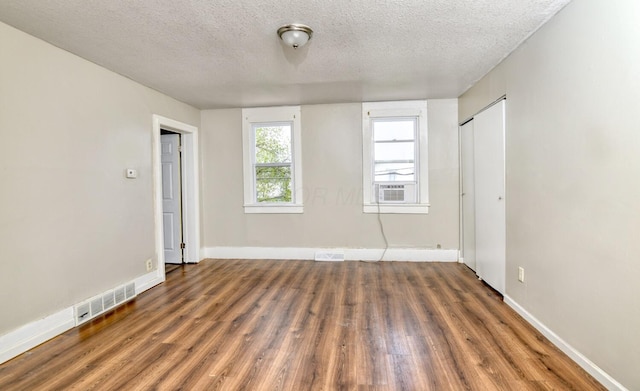 spare room with visible vents, wood finished floors, and a textured ceiling