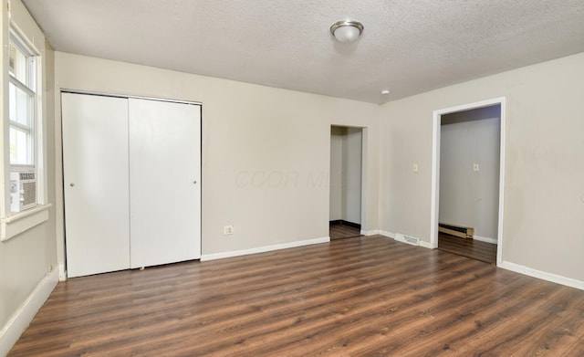 unfurnished bedroom with visible vents, baseboard heating, wood finished floors, and baseboards