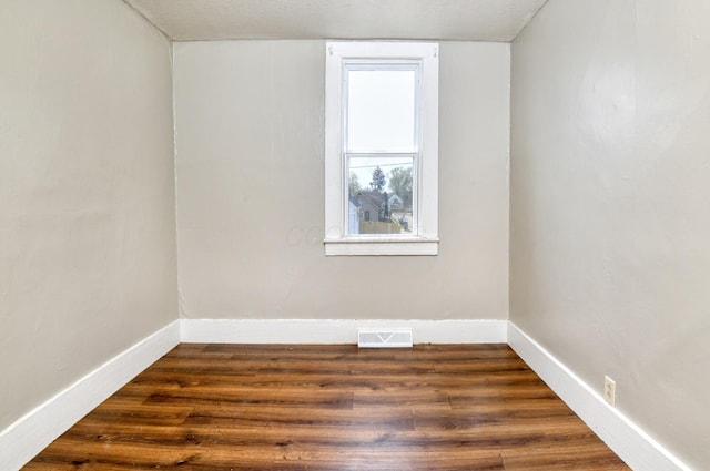 unfurnished room with visible vents, dark wood-style floors, and baseboards