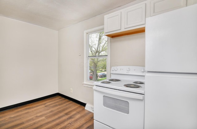 kitchen featuring dark wood finished floors, white appliances, light countertops, white cabinets, and baseboards