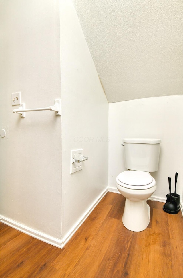 bathroom featuring a textured ceiling, baseboards, toilet, vaulted ceiling, and wood finished floors