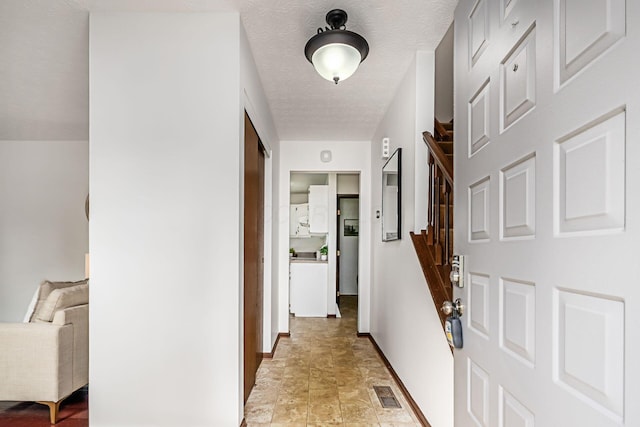 hall featuring baseboards, light stone finish flooring, and stairway