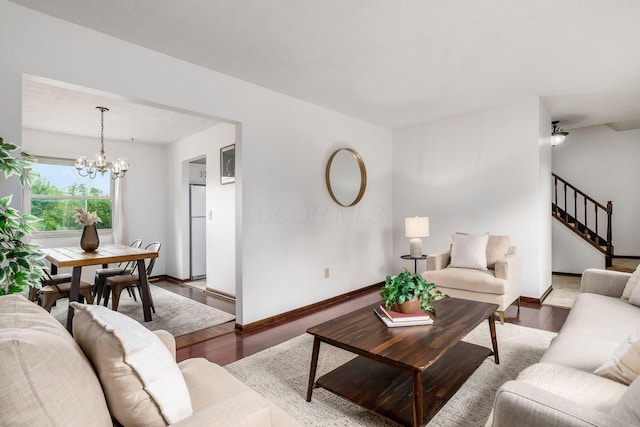 living room featuring stairway, wood finished floors, baseboards, and a chandelier