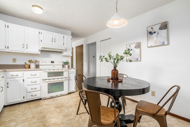 kitchen featuring range with two ovens, under cabinet range hood, light countertops, white cabinetry, and pendant lighting