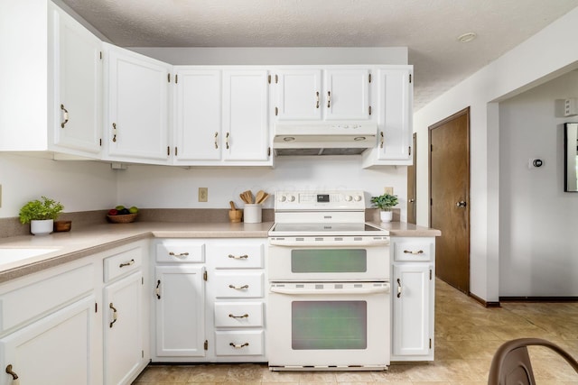 kitchen featuring double oven range, under cabinet range hood, white cabinetry, light countertops, and a textured ceiling