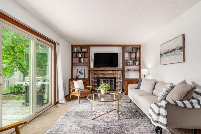 living room with a brick fireplace, carpet floors, and a textured ceiling