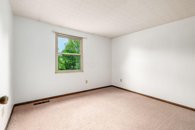 carpeted spare room featuring baseboards and a textured ceiling