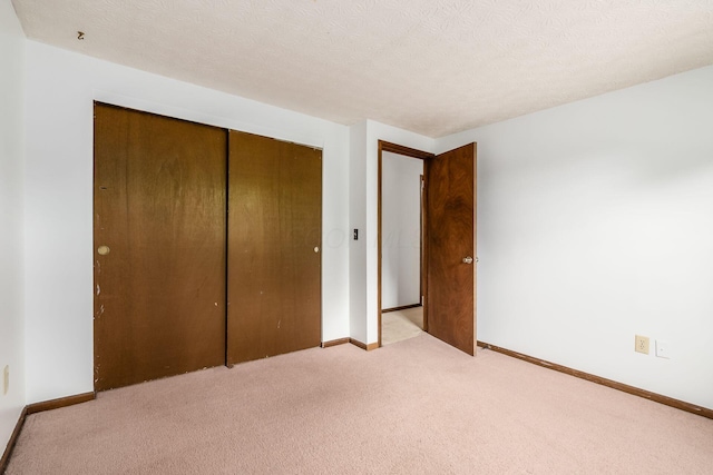 unfurnished bedroom with light carpet, a closet, and baseboards