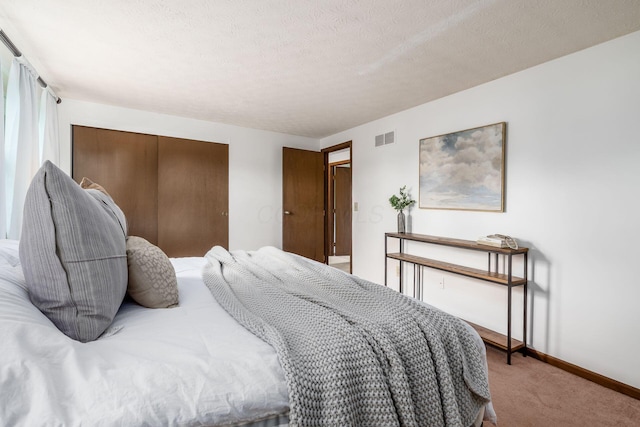 carpeted bedroom with baseboards, a closet, and a textured ceiling