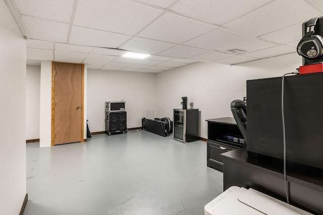 misc room featuring finished concrete floors, a paneled ceiling, and baseboards