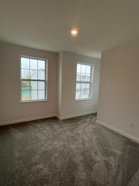 empty room with recessed lighting, dark colored carpet, and baseboards