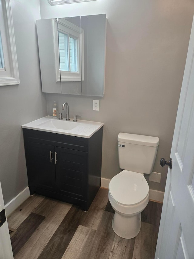 bathroom featuring wood finished floors, toilet, vanity, and baseboards