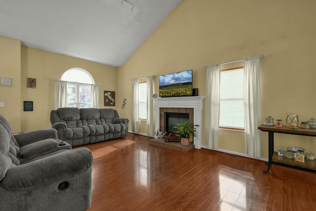 living room featuring visible vents, a fireplace, wood finished floors, track lighting, and high vaulted ceiling