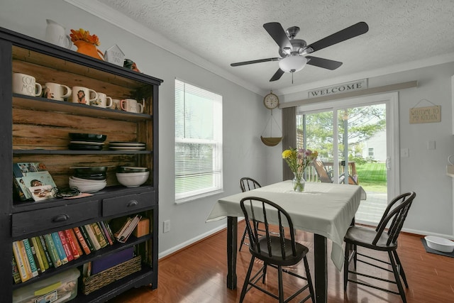 dining space with ceiling fan, a textured ceiling, wood finished floors, baseboards, and ornamental molding