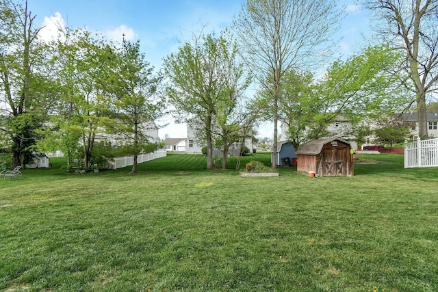 view of yard featuring fence, a storage unit, and an outdoor structure