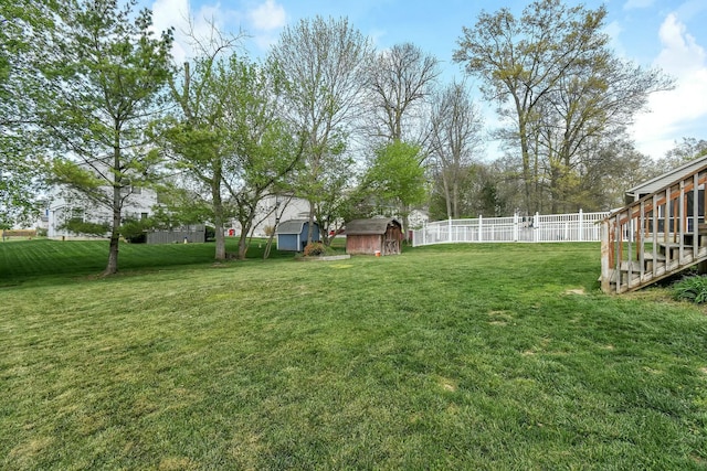 view of yard featuring a storage shed, fence, and an outbuilding