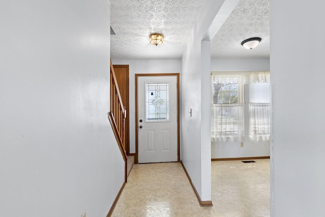 doorway featuring stairway, baseboards, a textured ceiling, and visible vents
