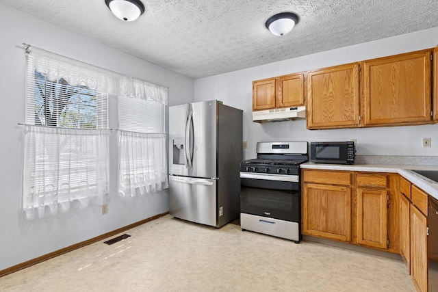 kitchen featuring light countertops, under cabinet range hood, brown cabinets, and stainless steel appliances